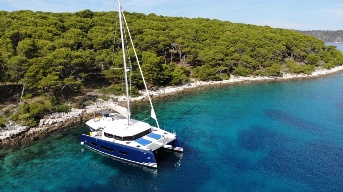 Segelkatamaran vid en grönskande vik i Kroatien